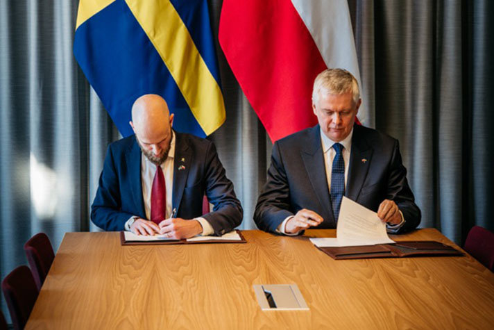 Carl-Oskar Bohlin and Tomasz Siemoniak signing papers.