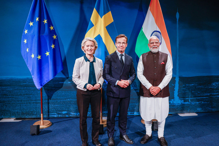 Prime Minister of Sweden, Premie Minister of India and President of the European Commission in front of flags.