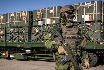 Soldier standing in front of a military transport.