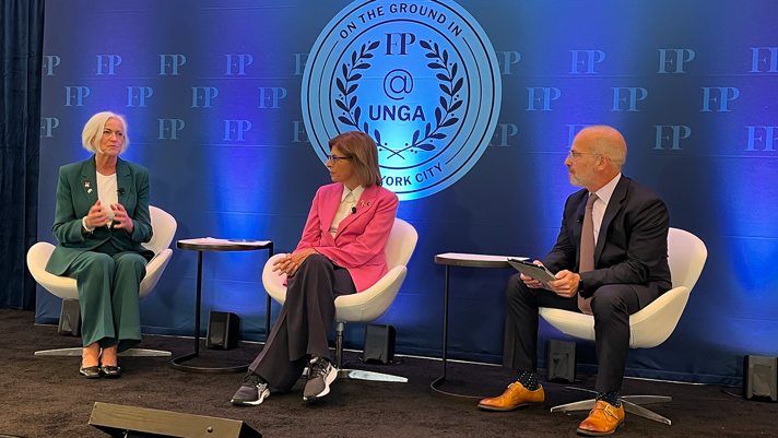 A panel with three people. Behind them a back drop with the text "FP"