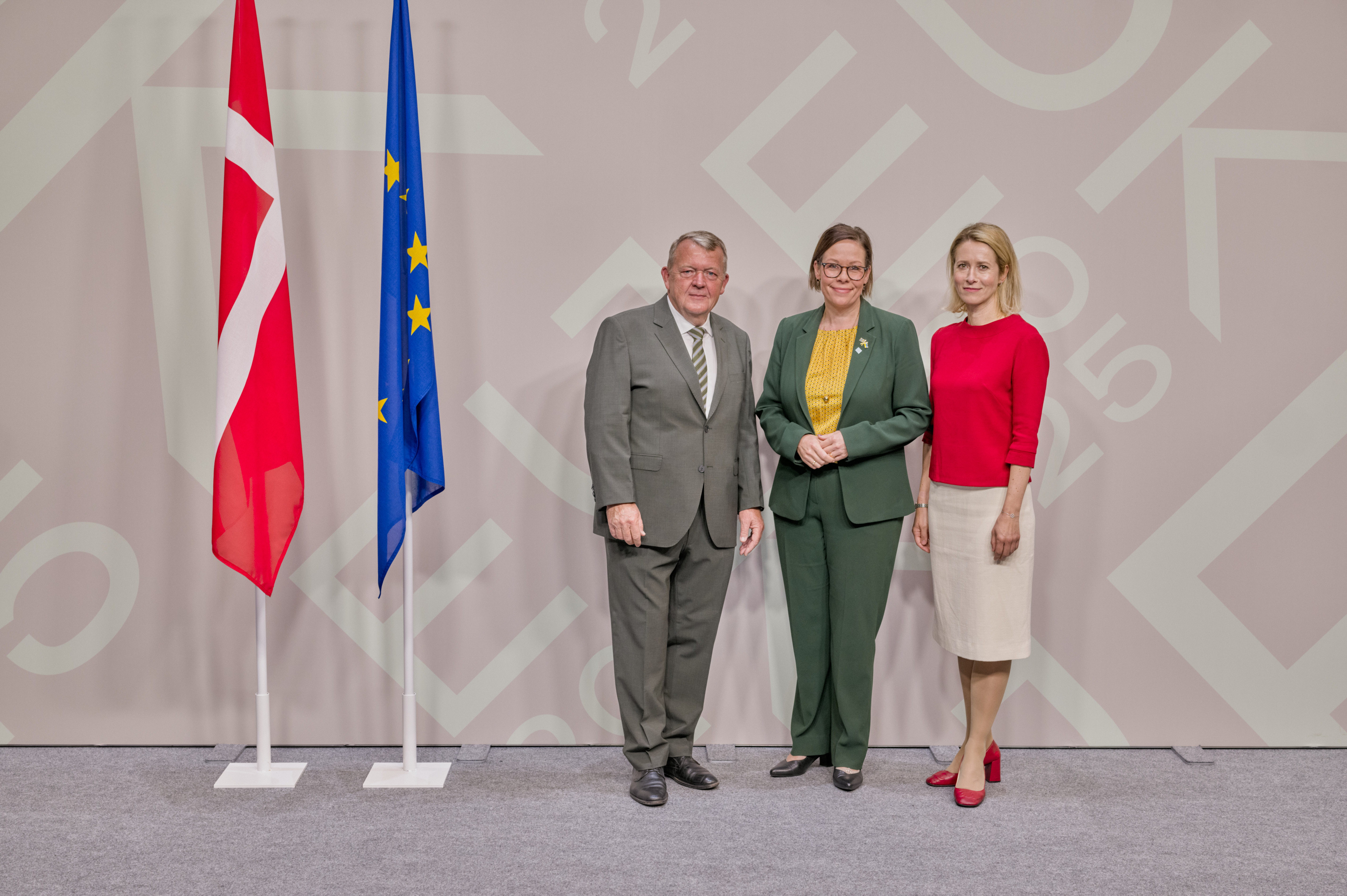 Maria Malmer Stenergard, Lars Løkke Rasmussen and Kaja Kallas posing in front of grey wall. 