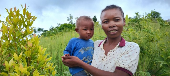 Woman holding a child in a field.